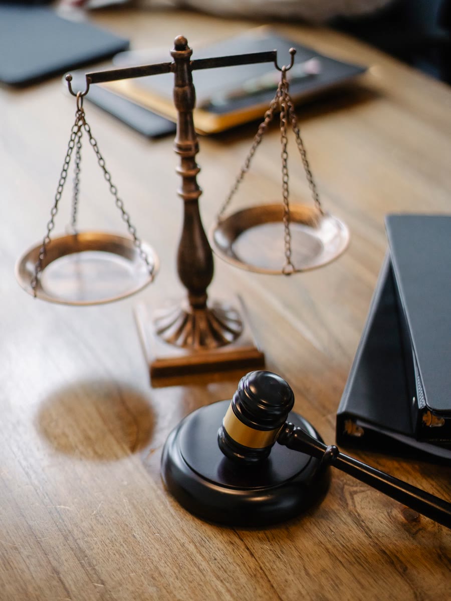 Balança da justiça em bronze sobre a mesa, ao lado de um martelo de juiz